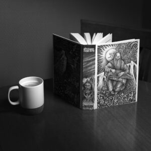 Відкрита книга «Кульгавець» з ілюстраціями поруч із чашкою на столі